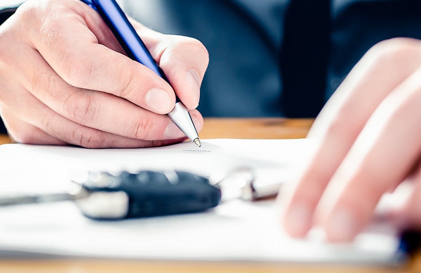a person signing a document with a key fob in front of them